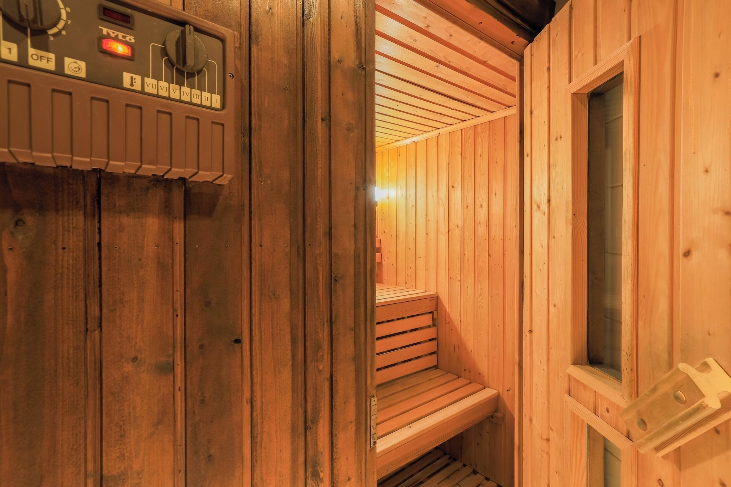 Puuseinäinen sauna, jossa on ohjauspaneeli.