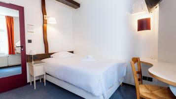Habitación de hotel con cama, mesita de noche, silla y televisión instalada en la pared.
