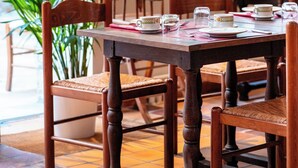 Een eethoek met houten stoelen en een gedekte tafel, omringd door potplanten en kunstwerken aan de muren.