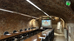 Une salle de conférence équipée d’une longue table, de chaises, d’un écran de projection et d’un tableau blanc.