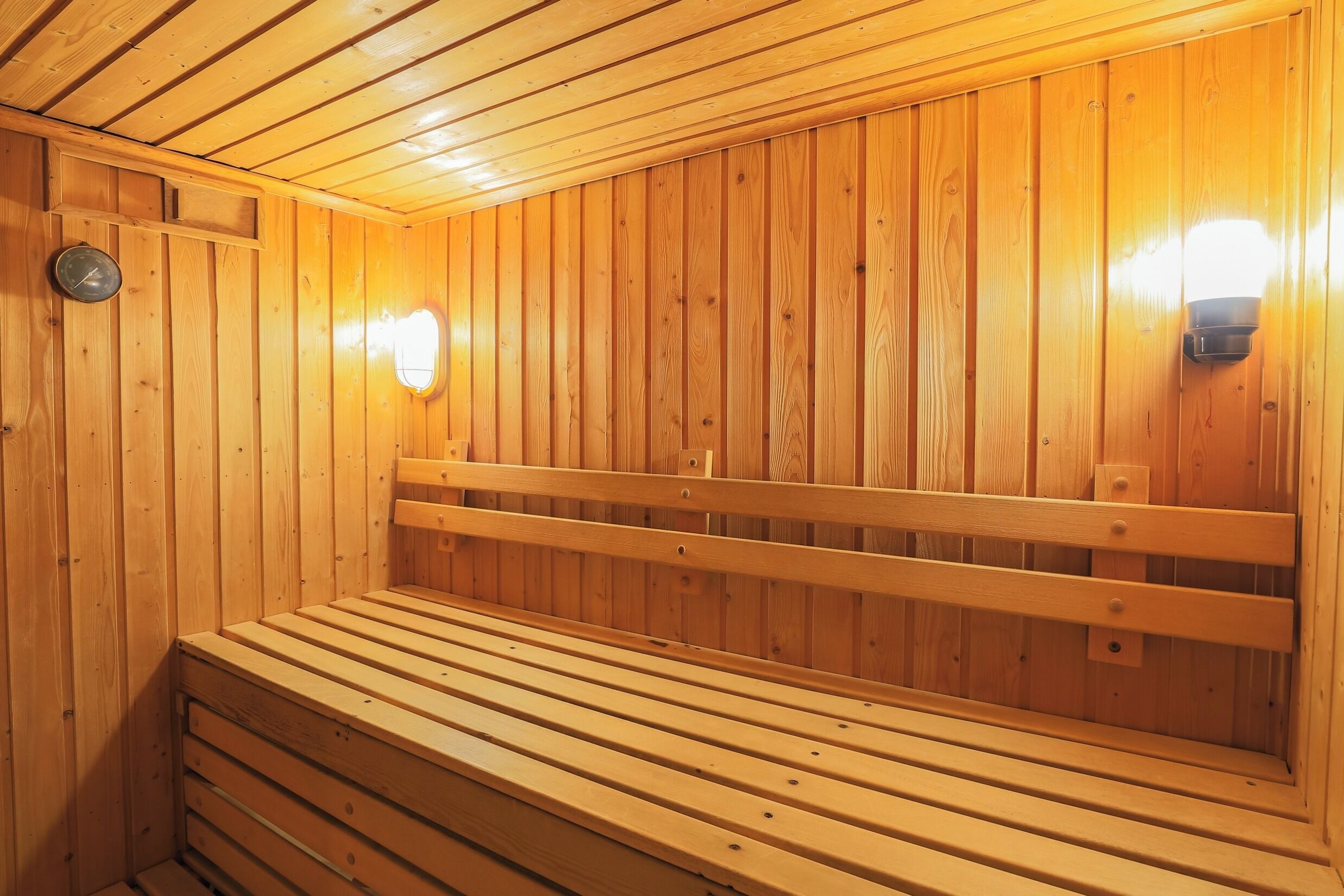 Una sauna de madera con bancos y luces en la pared.