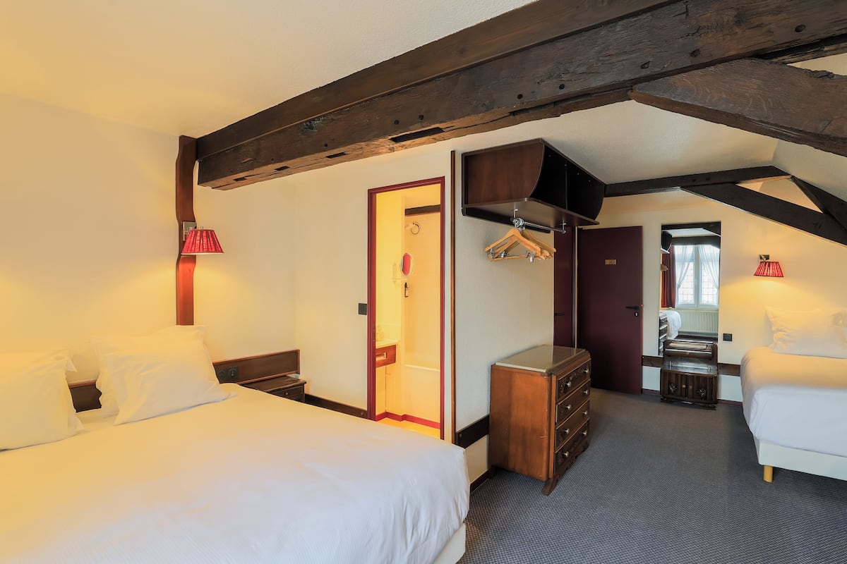 Una habitación de hotel con una cama grande, un aparador, un espejo y un perchero.