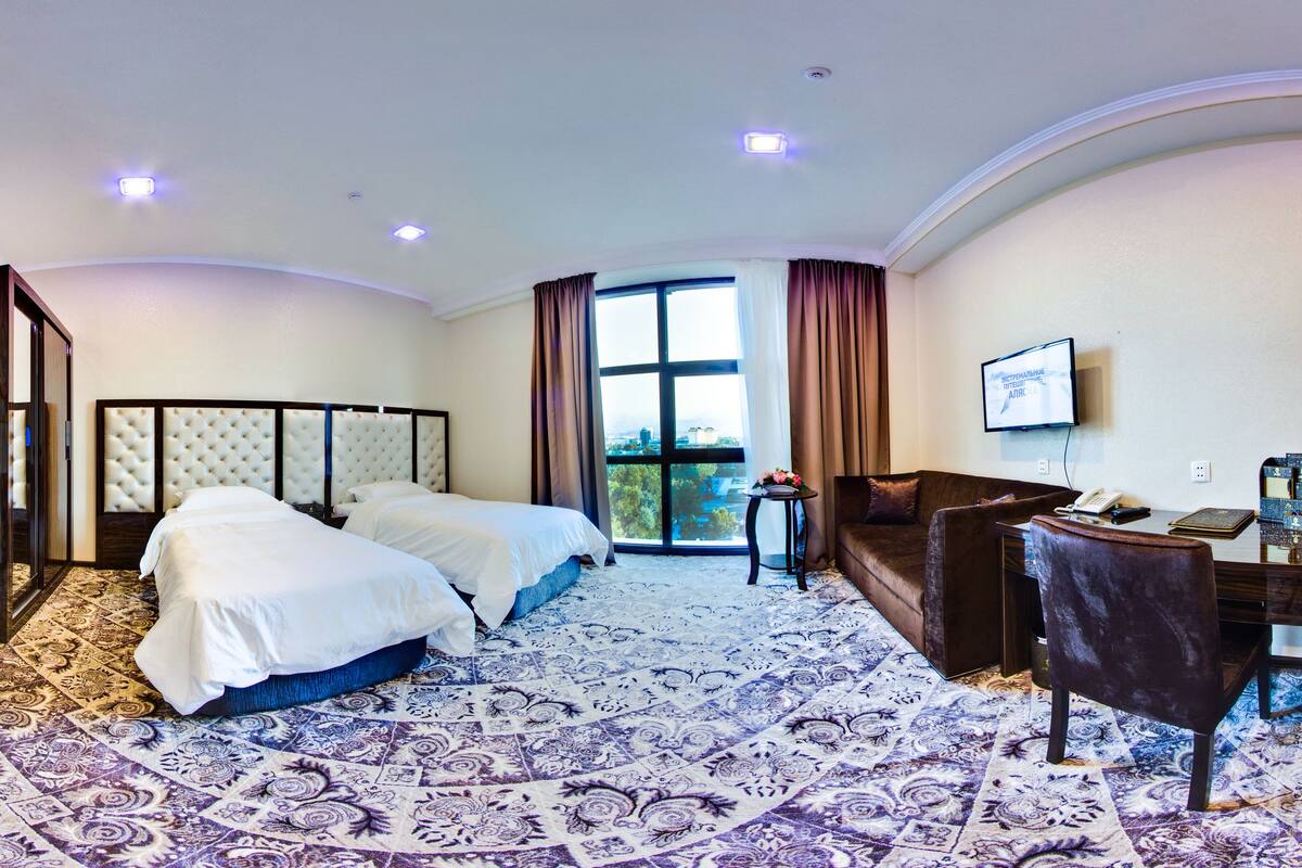 Une chambre d’hôtel avec un grand lit, un bureau, une chaise et un téléviseur.