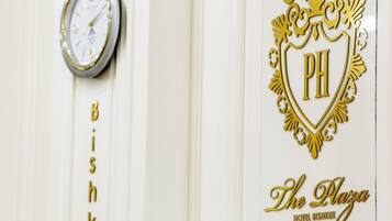Un mur orné d’une horloge et d’une enseigne indiquant « The Plaza Hotel Bishkek ».