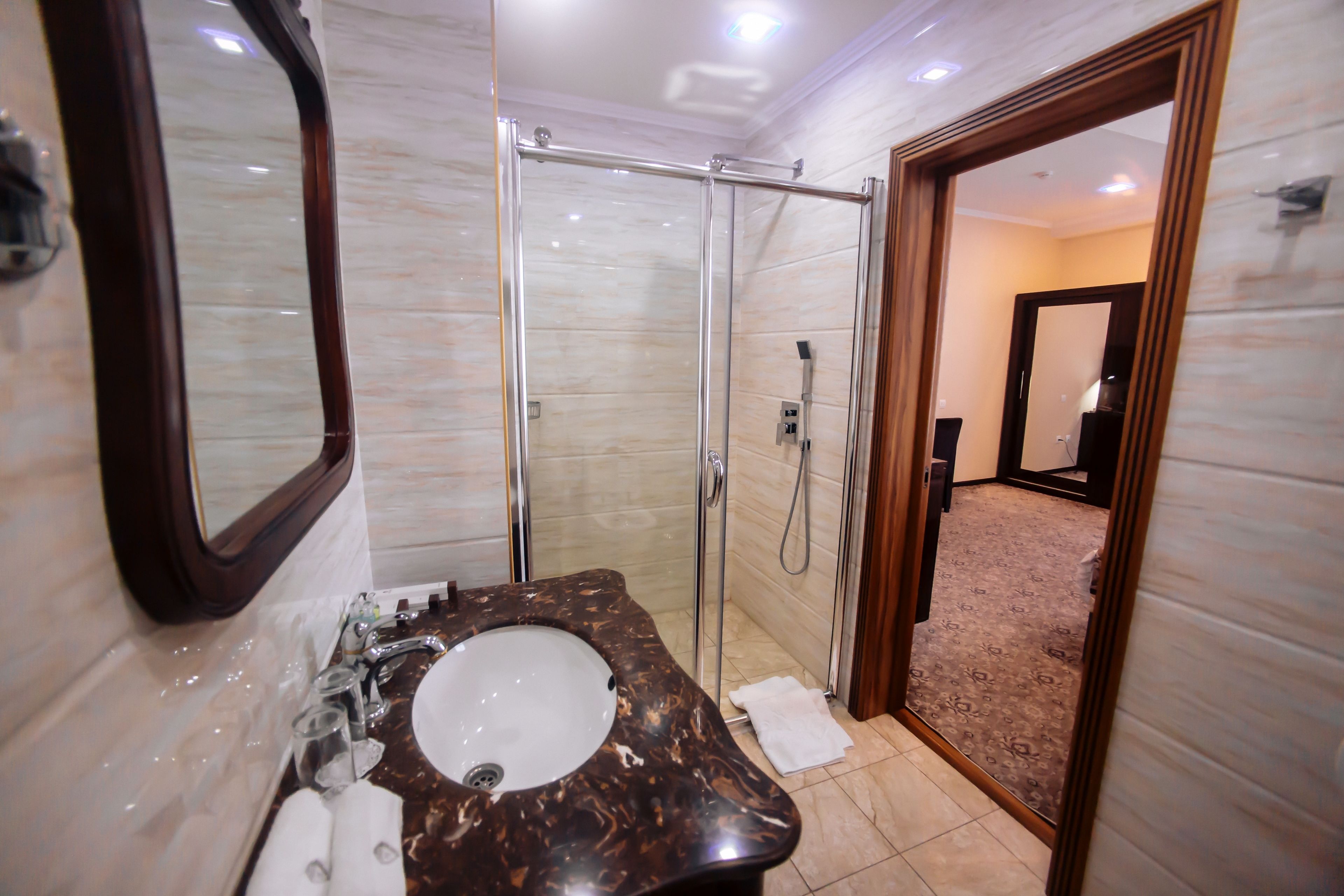 Un baño con lavabo de mármol, cabina de ducha de vidrio y espejo.