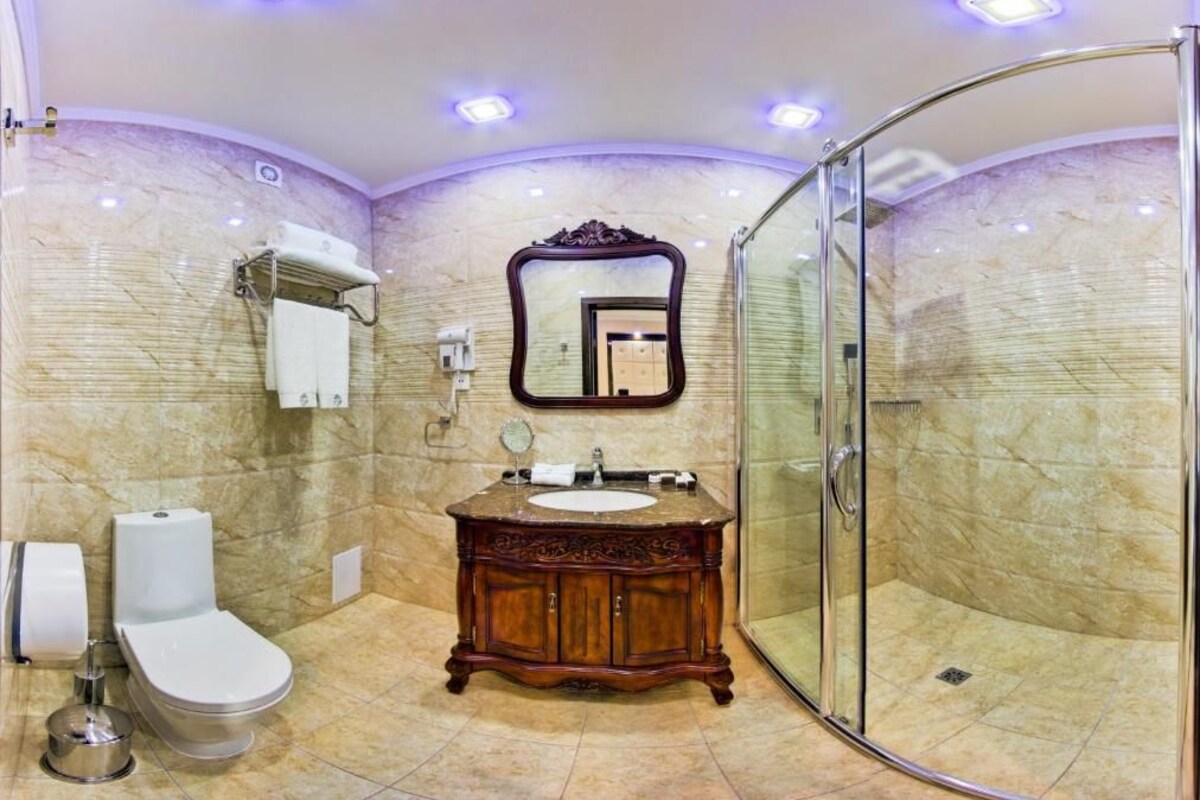 Une salle de bain avec un meuble-lavabo en marbre, une cabine de douche en verre et des toilettes.
