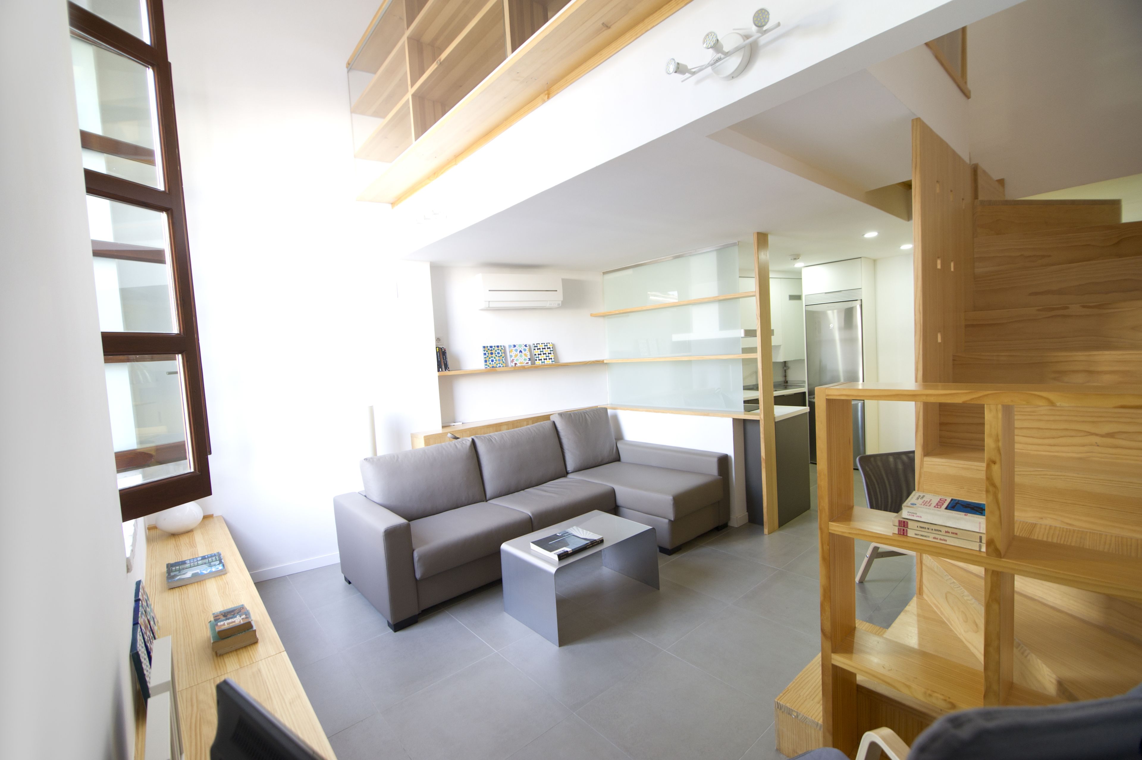 Una sala de estar moderna con un sofá seccional gris, una mesita de centro y una estantería de madera.