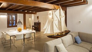 A spacious living area with a high ceiling, a dining table, a sofa, and a sailboat model. - Smart Suites Albaicin Apartamentos (Granada)