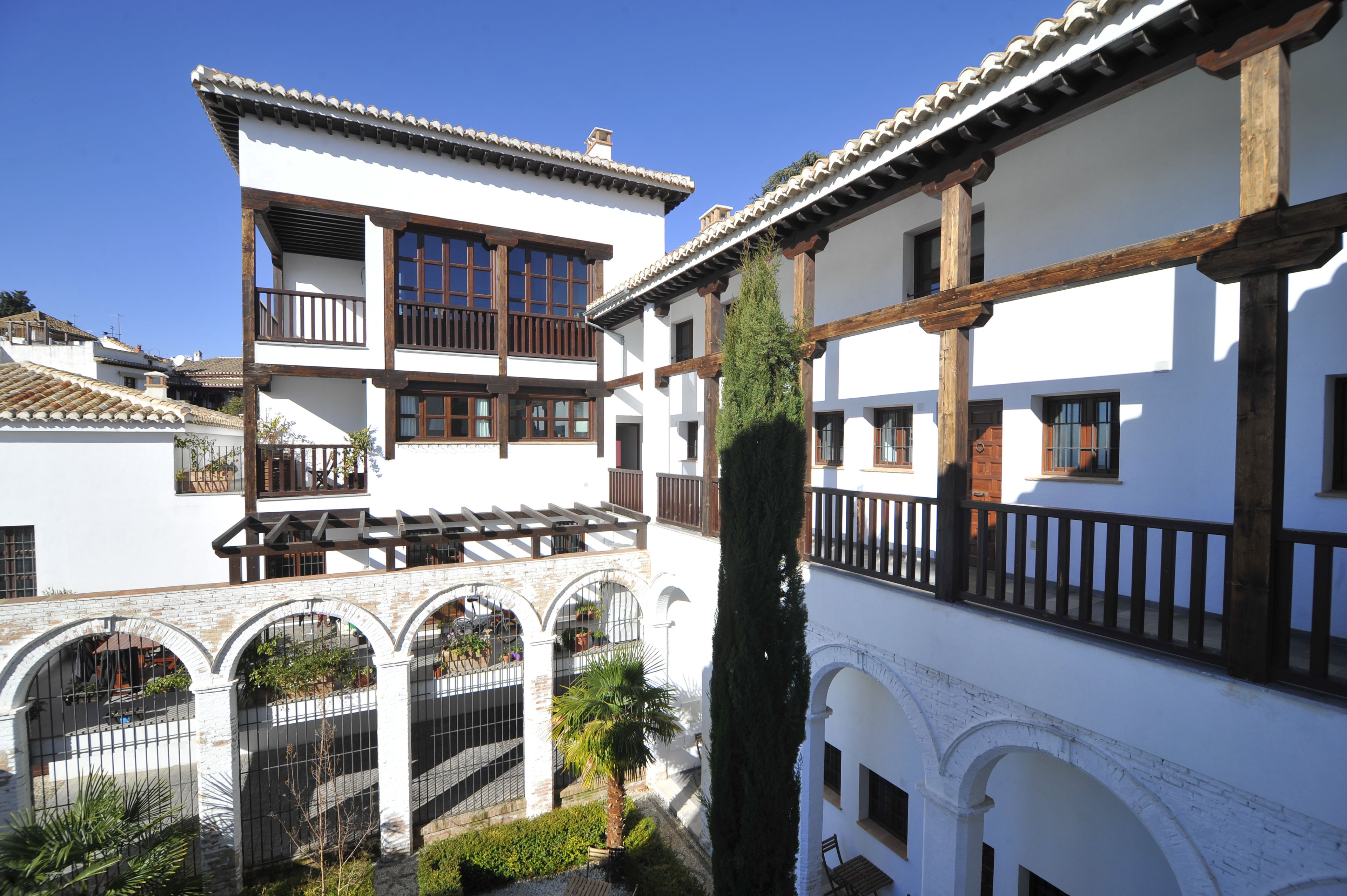 Un edificio tradicional con varios balcones, ventanas arqueadas y un patio con plantas.