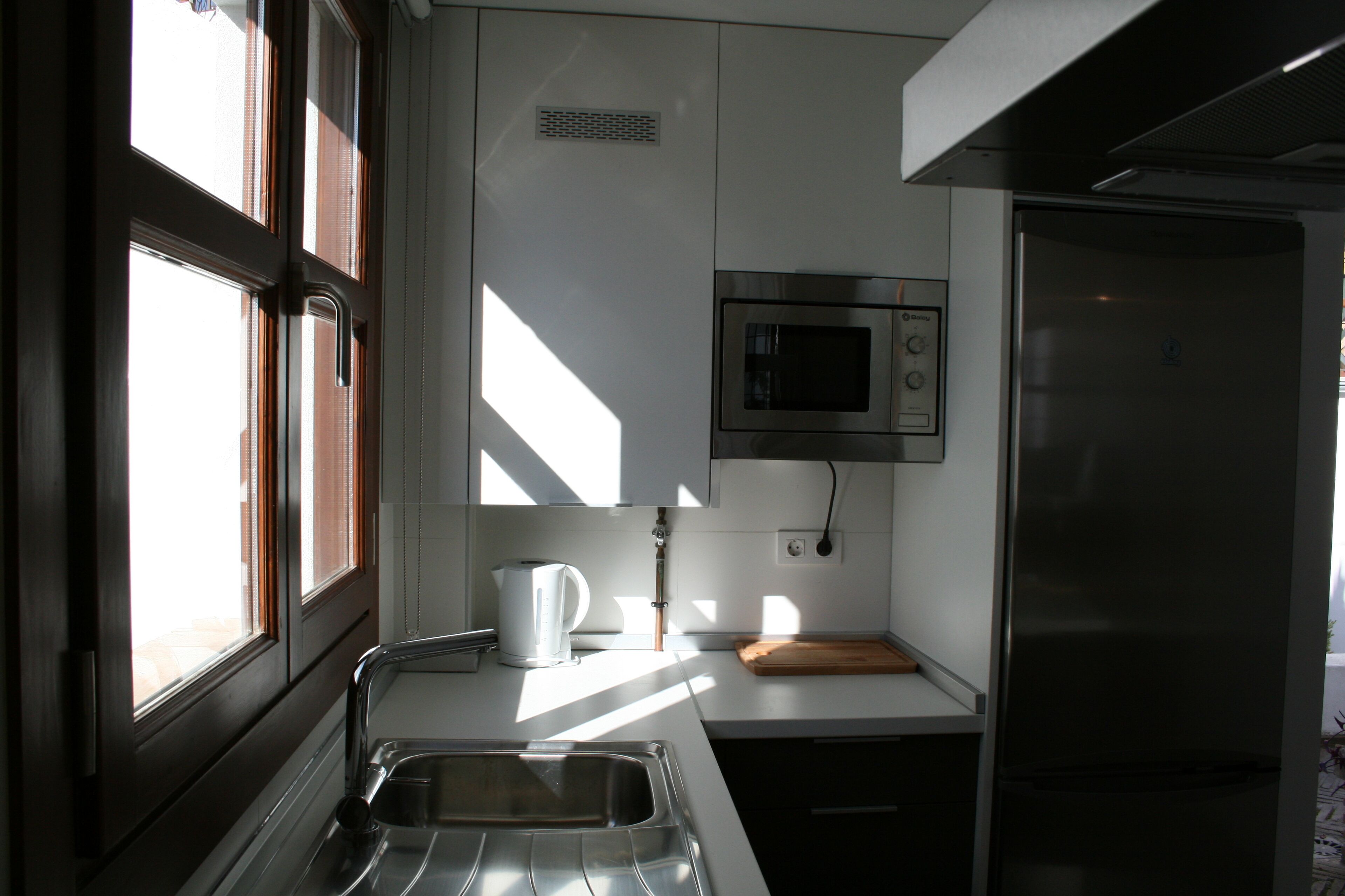 A modern kitchen with a stainless steel sink, a microwave, and a refrigerator.