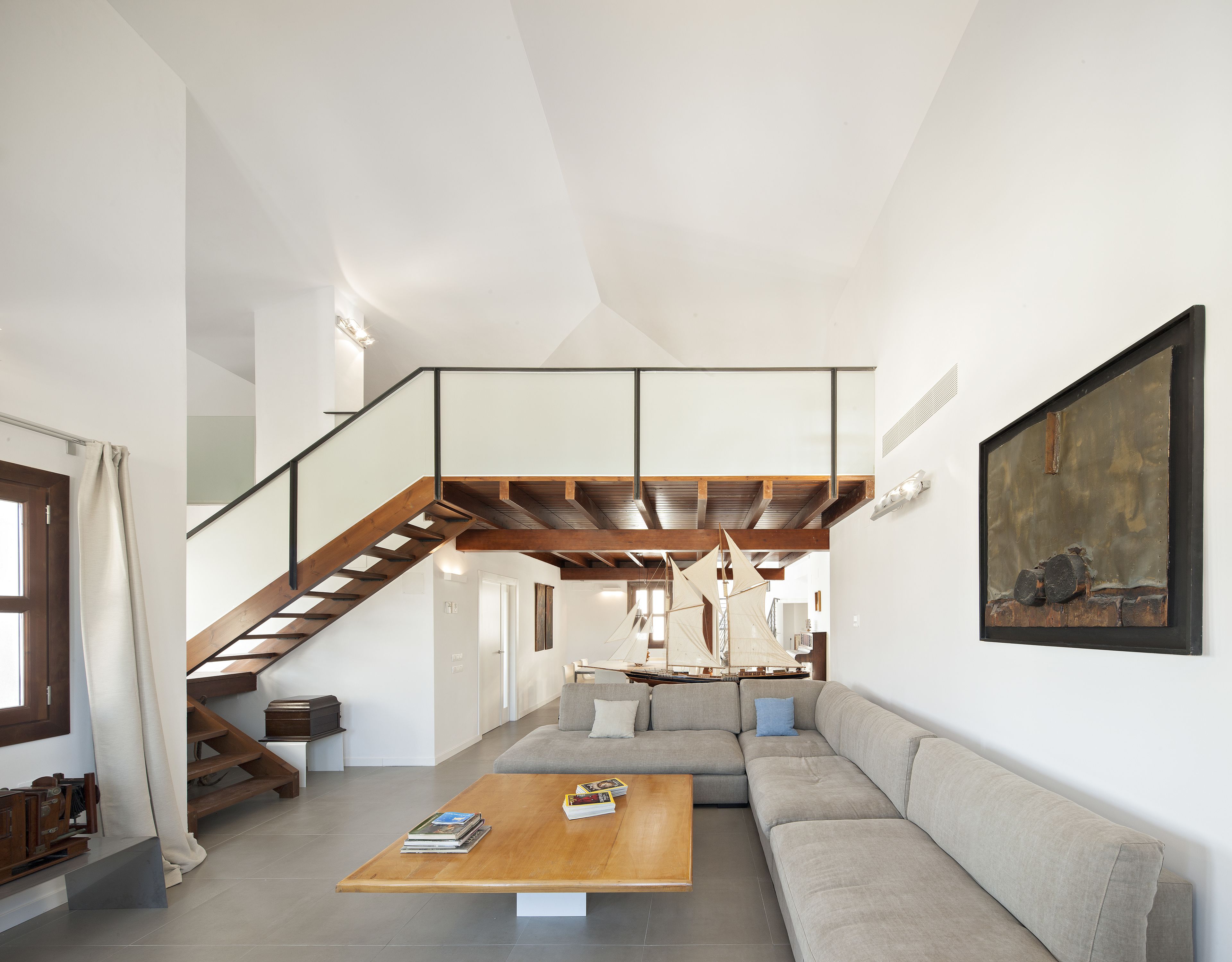 A spacious living area with a wooden staircase, a large sofa, and a coffee table.