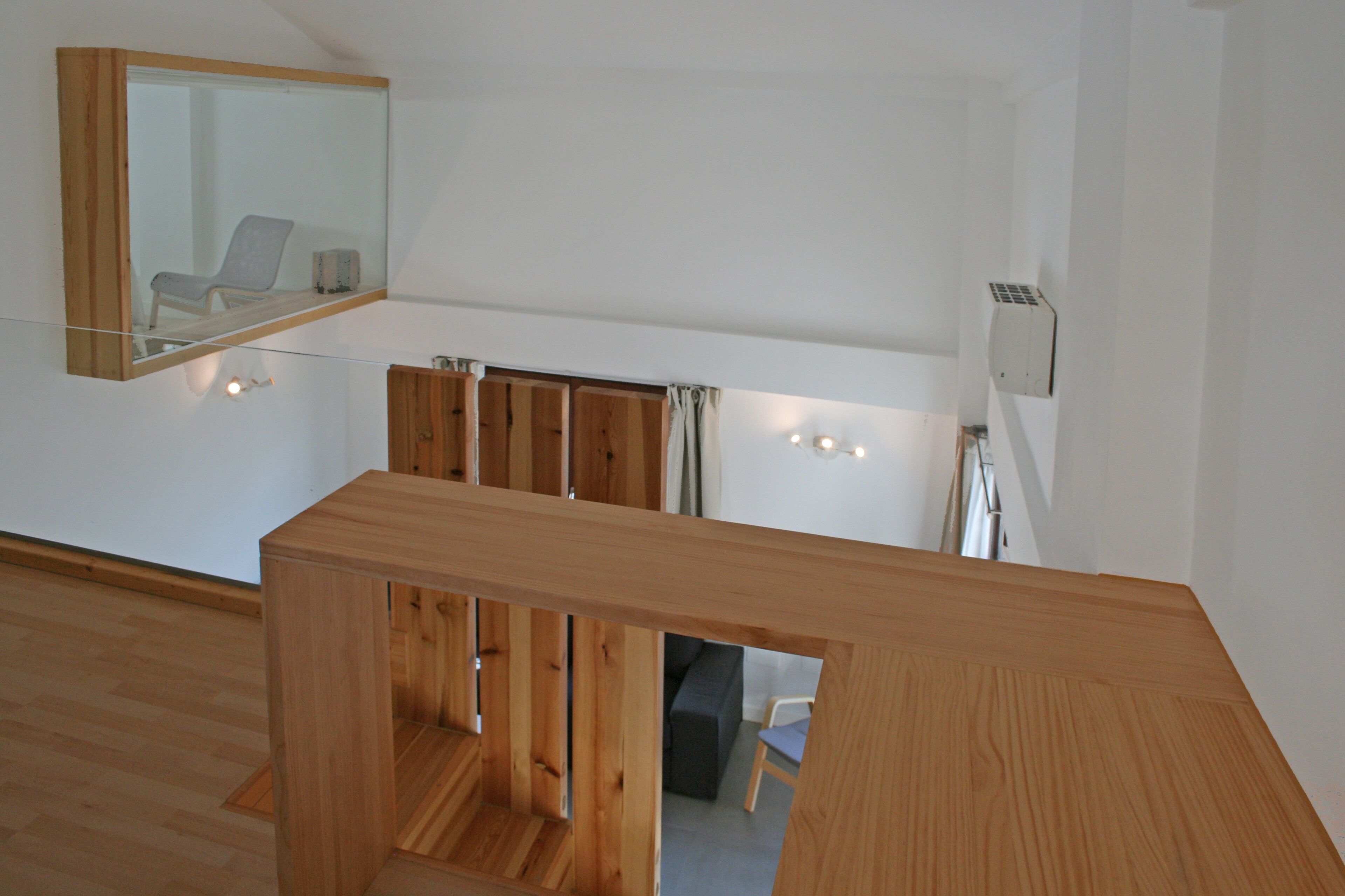 Un interior moderno con una mesa de madera, un espejo y vistas de una habitación con una silla y un sofá.