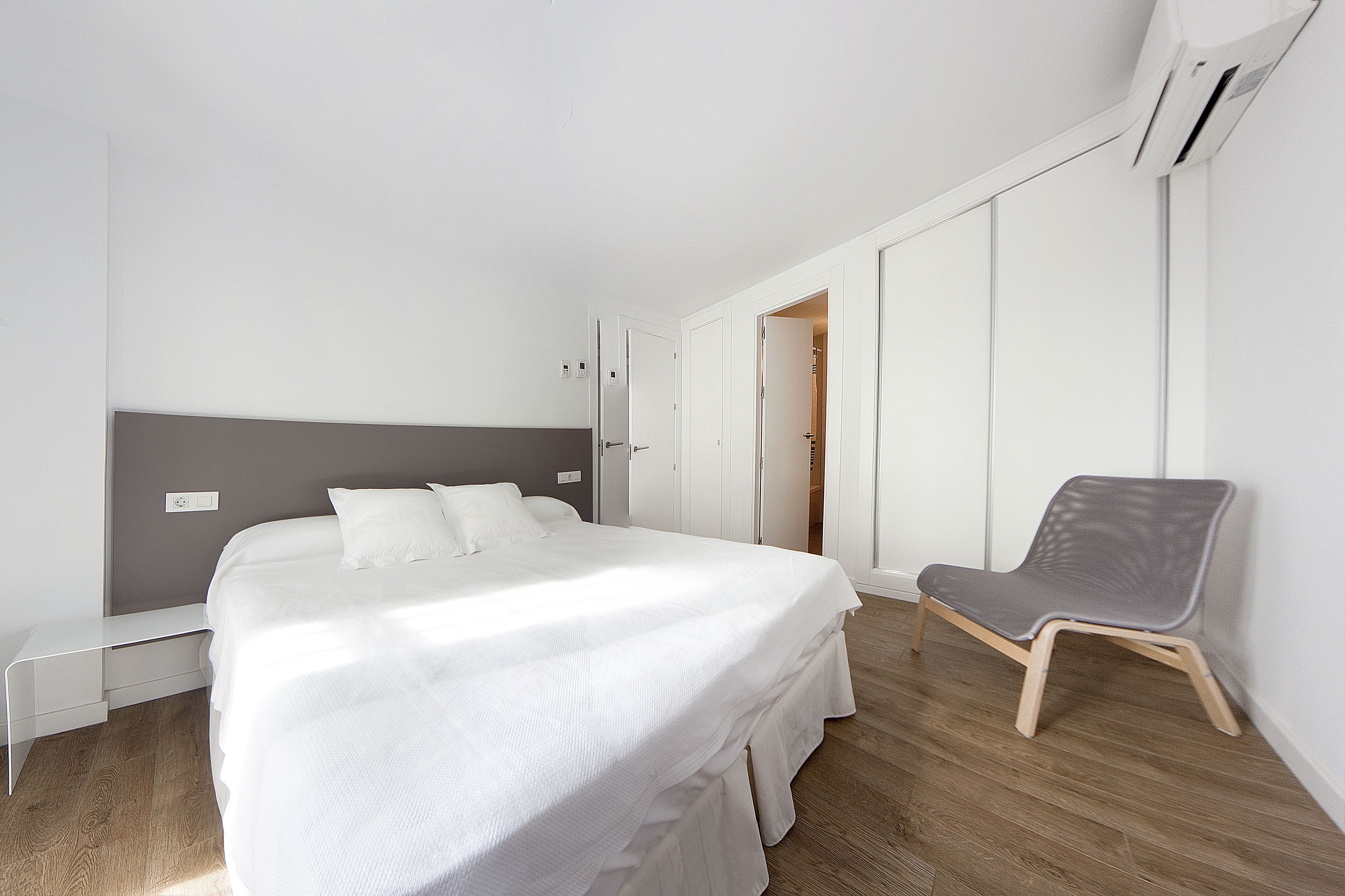 A modern bedroom with a bed, a chair, and a wardrobe.