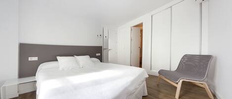 A modern bedroom with a bed, a chair, and a wardrobe.