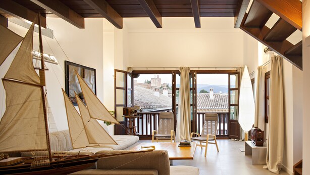 A spacious living room with a large window, a sailboat model, and a sofa. - Smart Suites Albaicin Apartamentos (Granada)