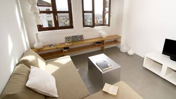 Una sala de estar moderna con un sofá, una mesa de centro, un mueble para televisión y un ventanal con vista a la ciudad.
