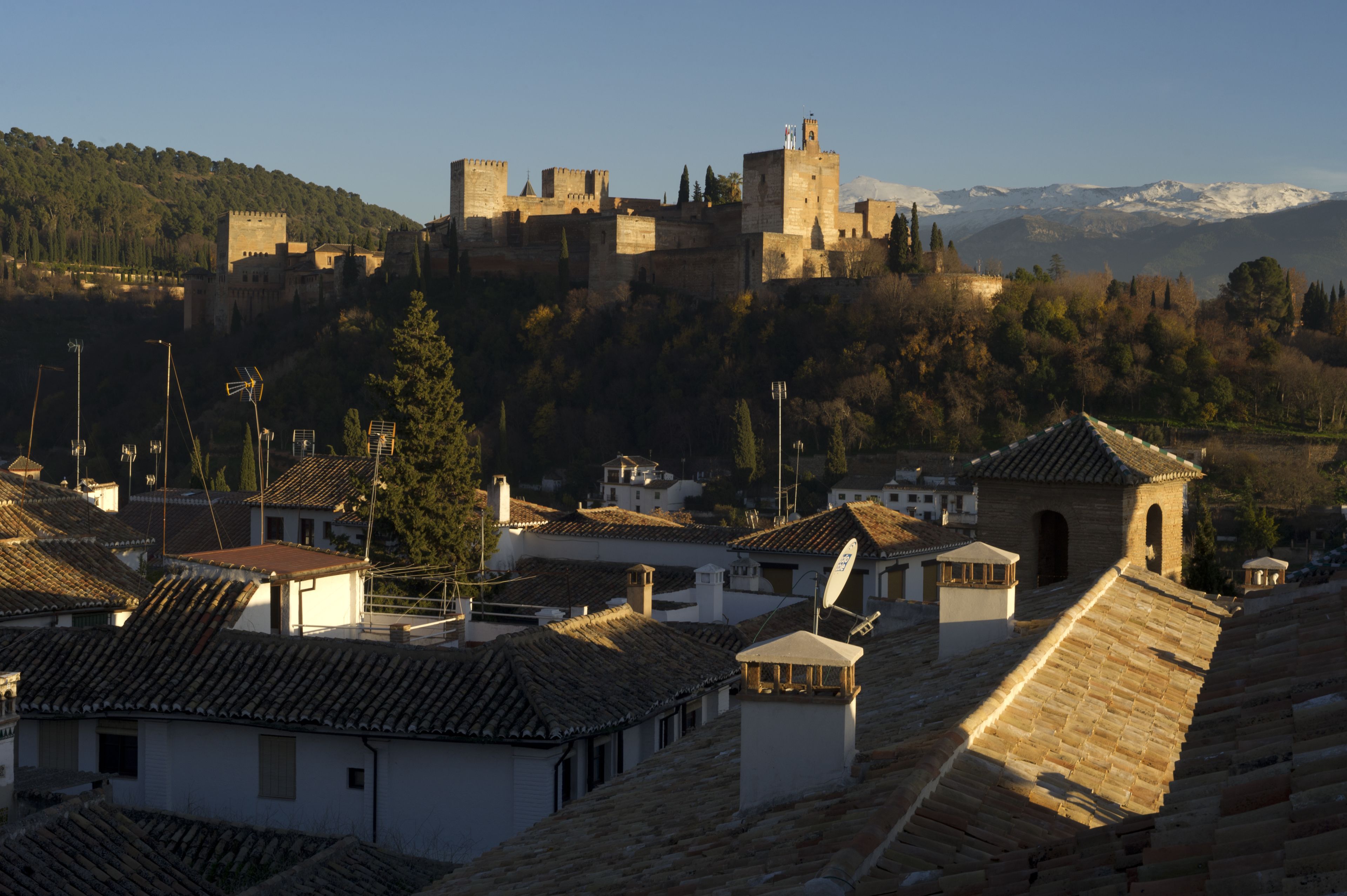 Un castillo histórico en una colina con vistas a un pueblo de techos de tejas tradicionales.