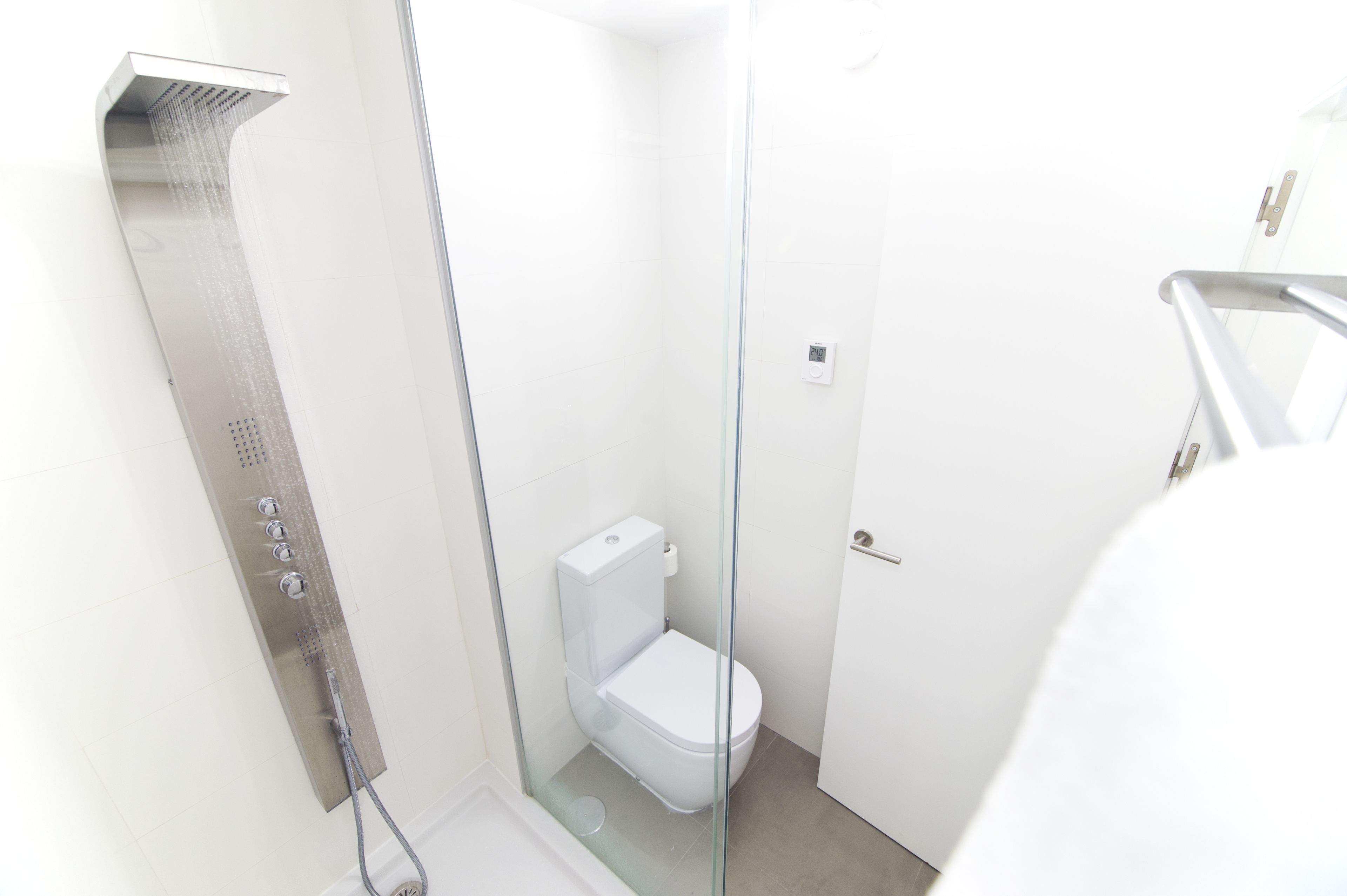 Un baño moderno con ducha de vidrio, inodoro blanco y puerta de vidrio.