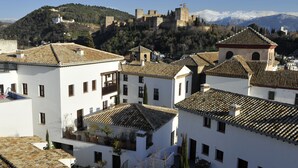A historic town with white buildings, a prominent castle on a hill, and snow-capped mountains in the background. - Smart Suites Albaicin Apartamentos (Granada)