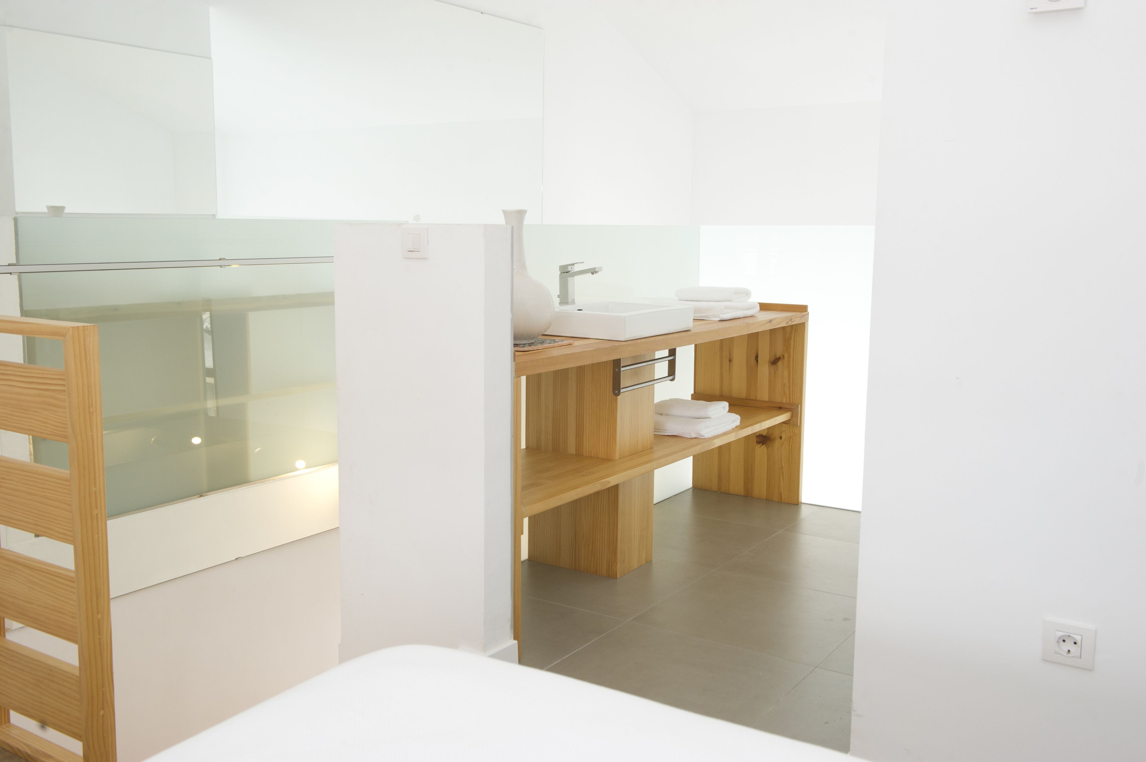 Een moderne badkamer met een douchecabine van glas, een houten wastafelmeubel met een wastafel en handdoekhouder, en een wit toilet.