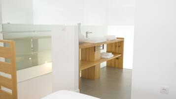 Een moderne badkamer met een douchecabine van glas, een houten wastafelmeubel met een wastafel en handdoekhouder, en een wit toilet.