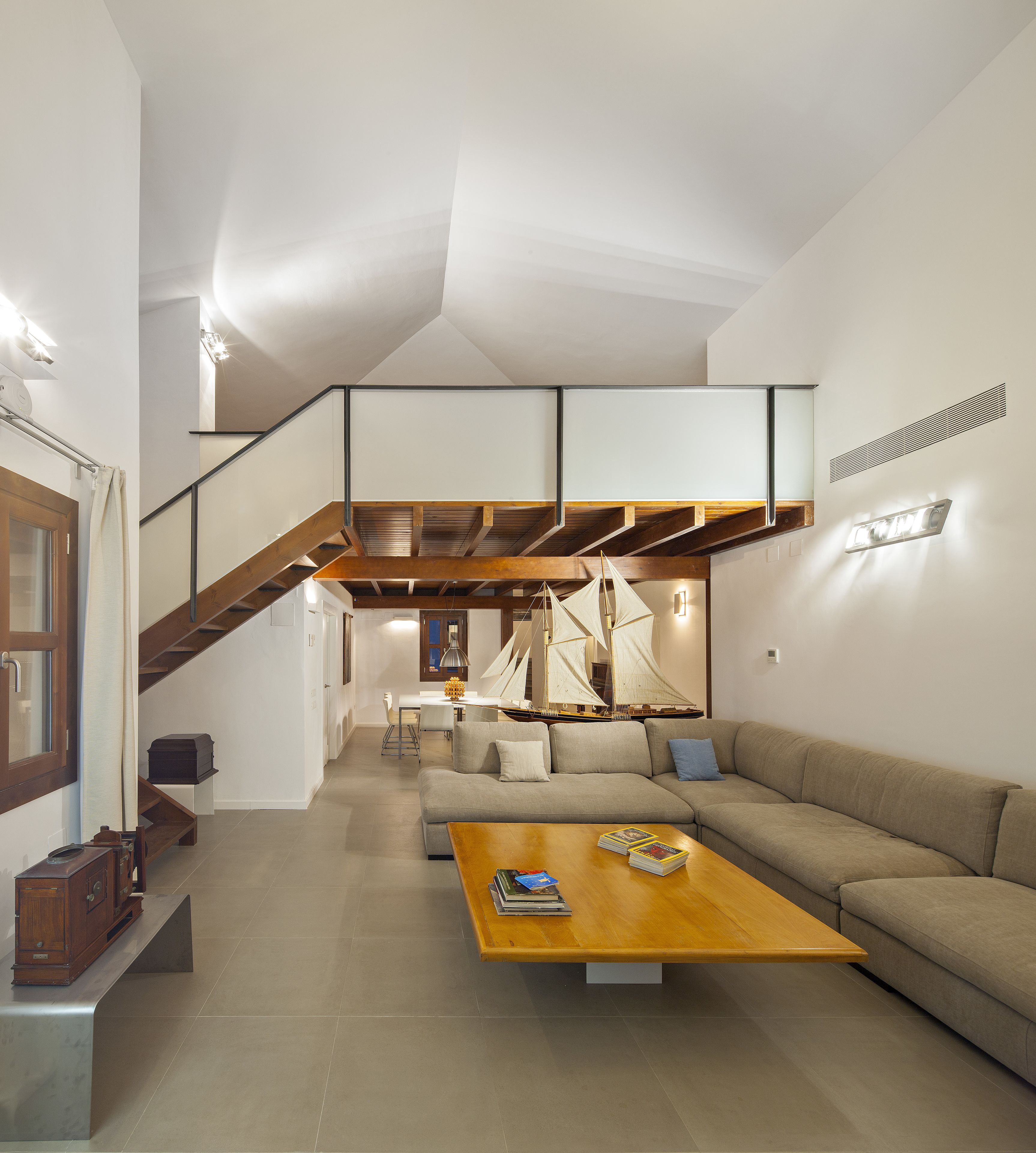 Un salon moderne avec un escalier en bois, un coin repas et une grande fenêtre.