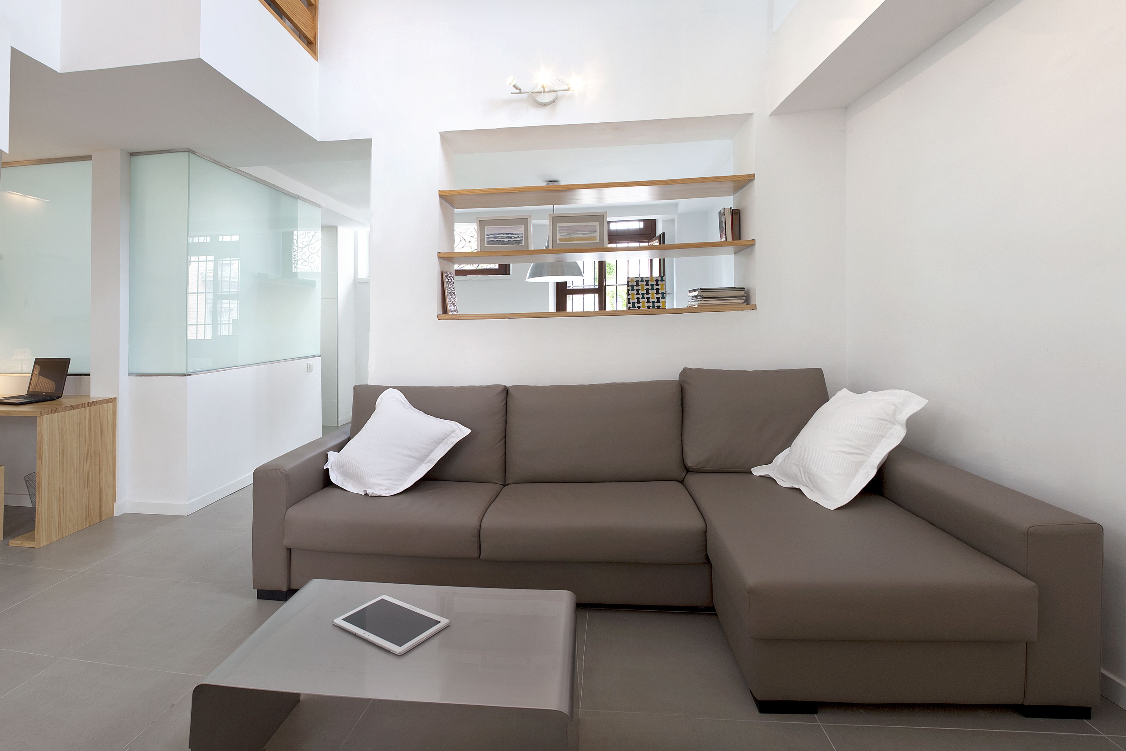 Een moderne woonkamer met een modulaire bank, een salontafel en een glazen scheidingswand.