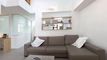 Un salon moderne avec un canapé d’angle, une table basse et une cloison en verre.