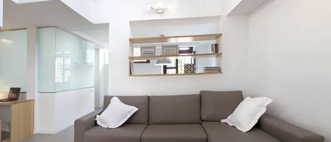 Een moderne woonkamer met een modulaire bank, een salontafel en een glazen scheidingswand.