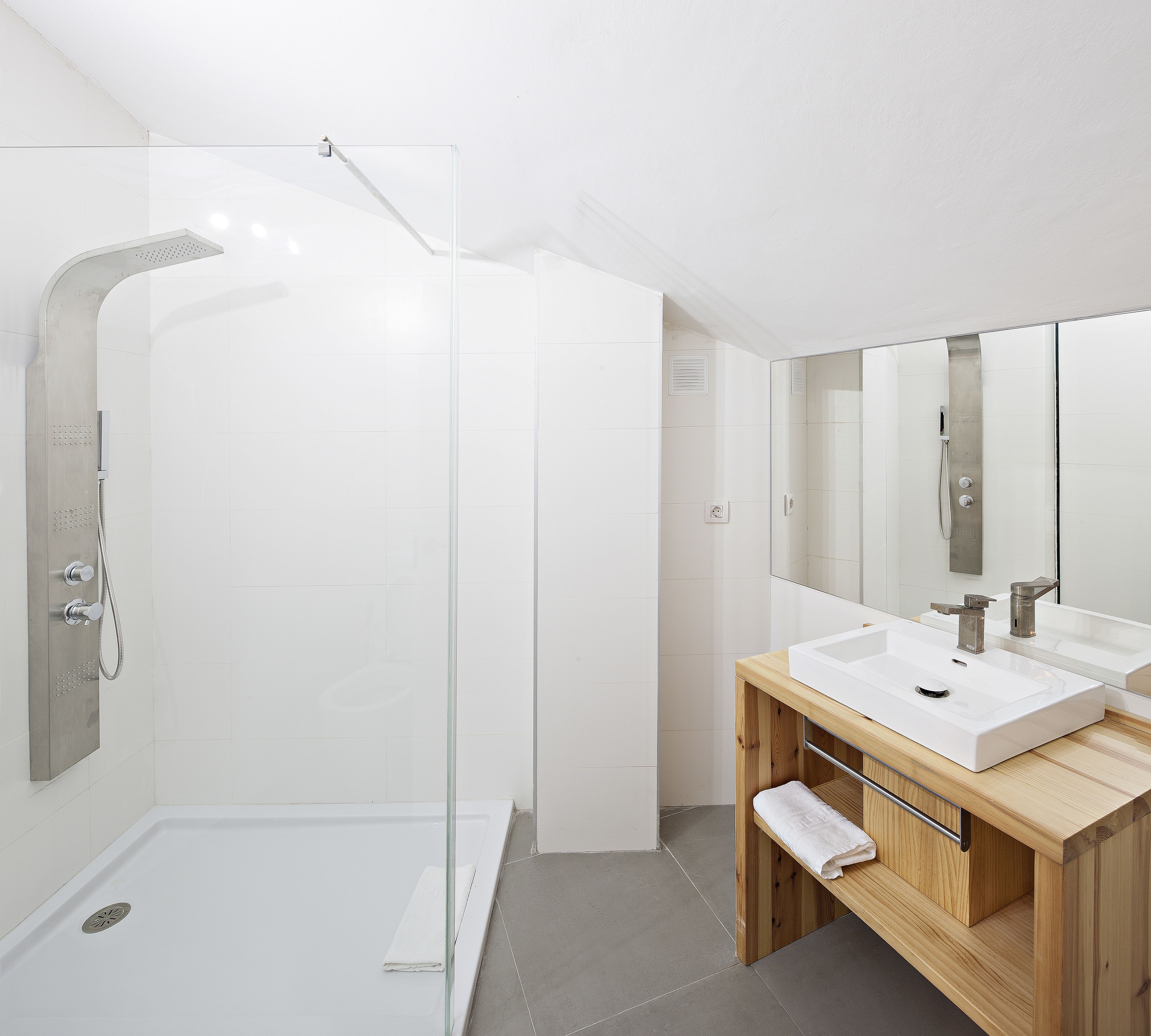 Une salle de bain moderne avec une douche à parois de verre, un meuble-lavabo en bois doté de deux vasques et un grand miroir.