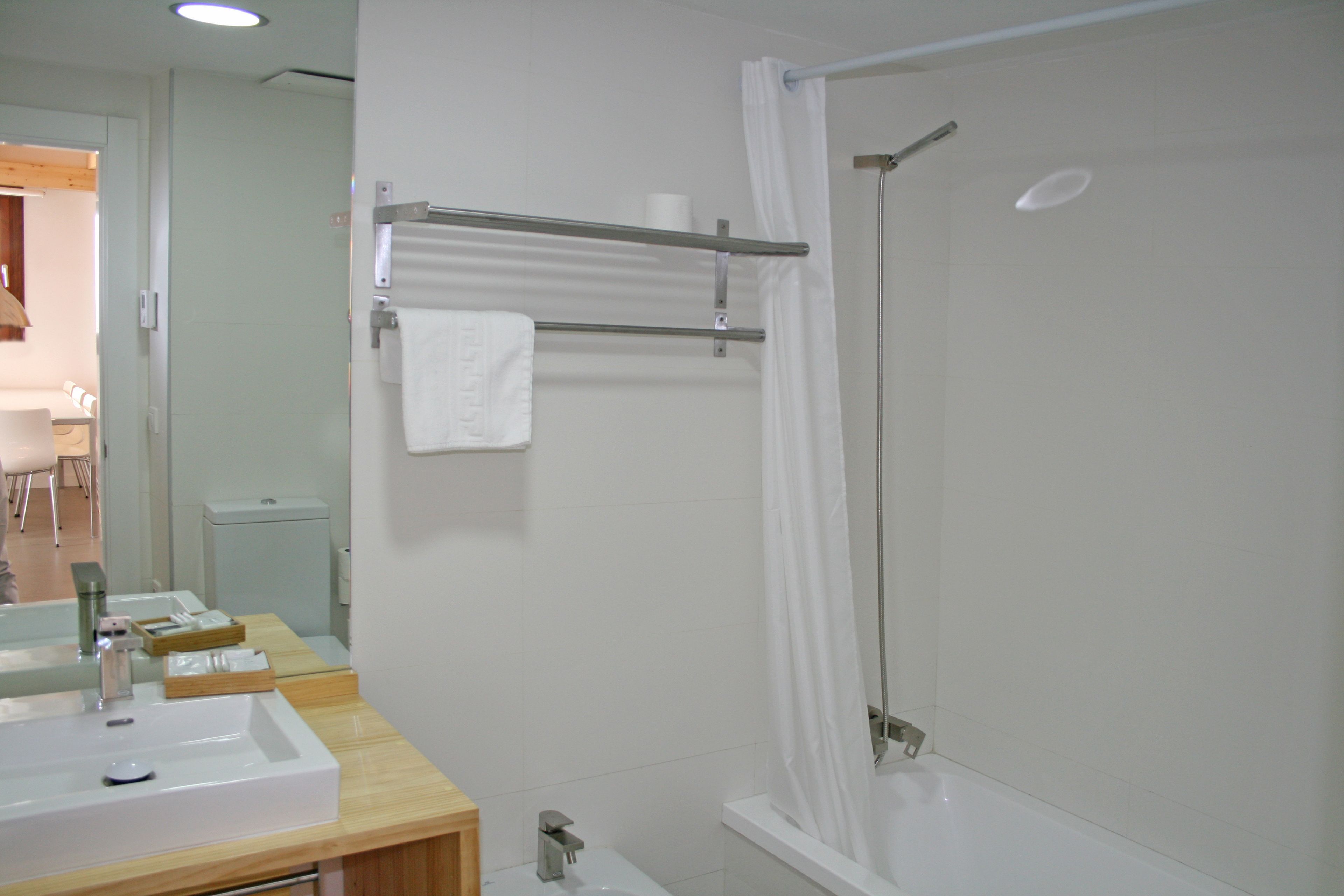 A modern bathroom with a white sink, mirror, and shower.