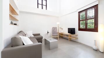 Una sala de estar moderna con un sofá, una mesa de centro, un televisor y una estantería.