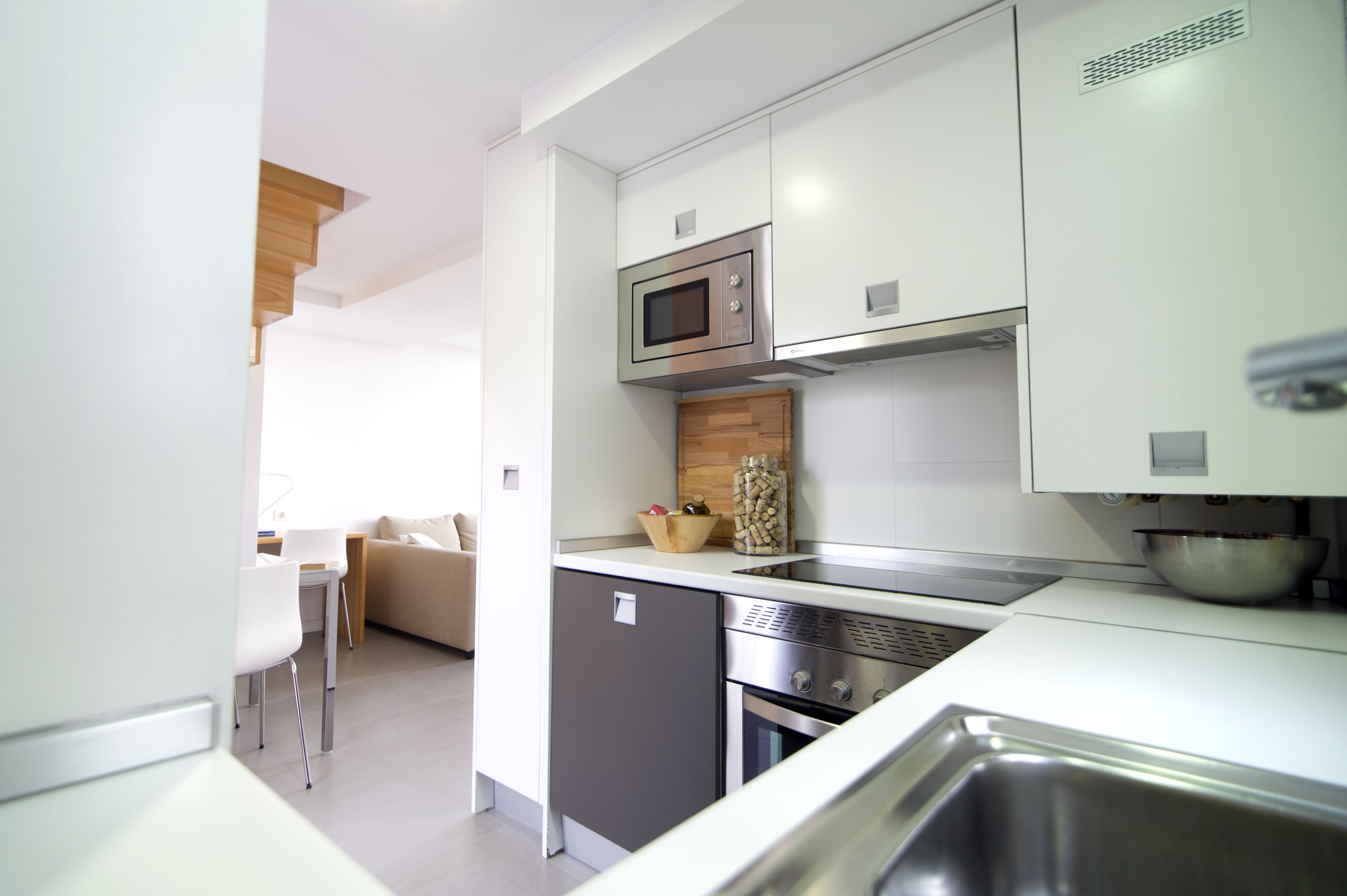 Una cocina moderna con armarios blancos, un microondas, una estufa y un lavabo.