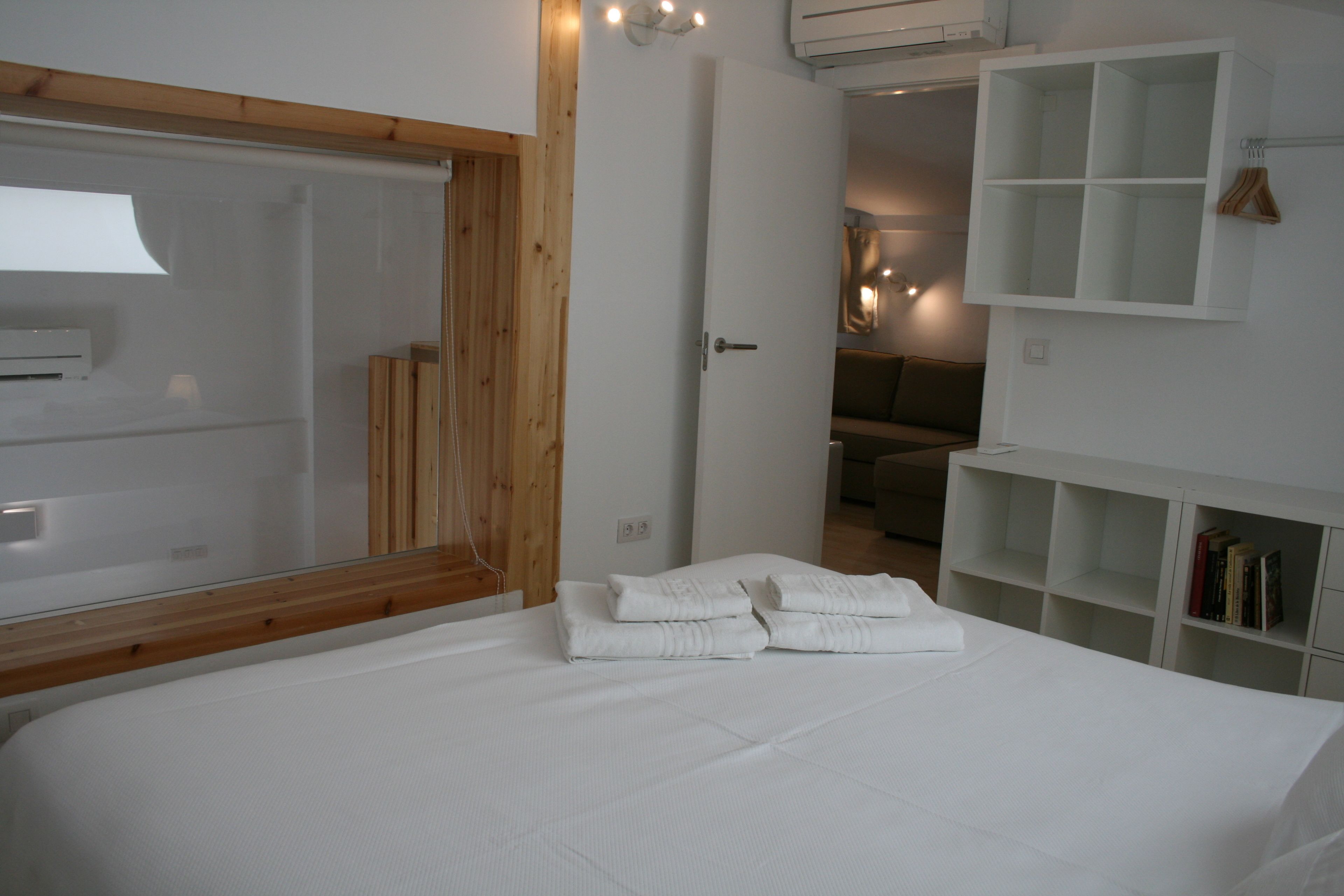 Une chambre à coucher avec un grand lit, une tête de lit en bois, une armoire blanche et une étagère intégrée remplie de livres.