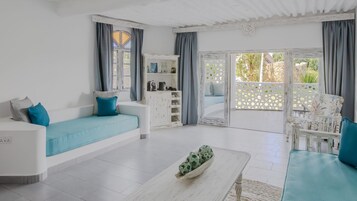 Un salón amplio con un sofá blanco, una mesita de centro y vistas a un área exterior a través de un ventanal.