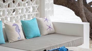 A white outdoor seating area with cushions and a small table with decorative tiles.