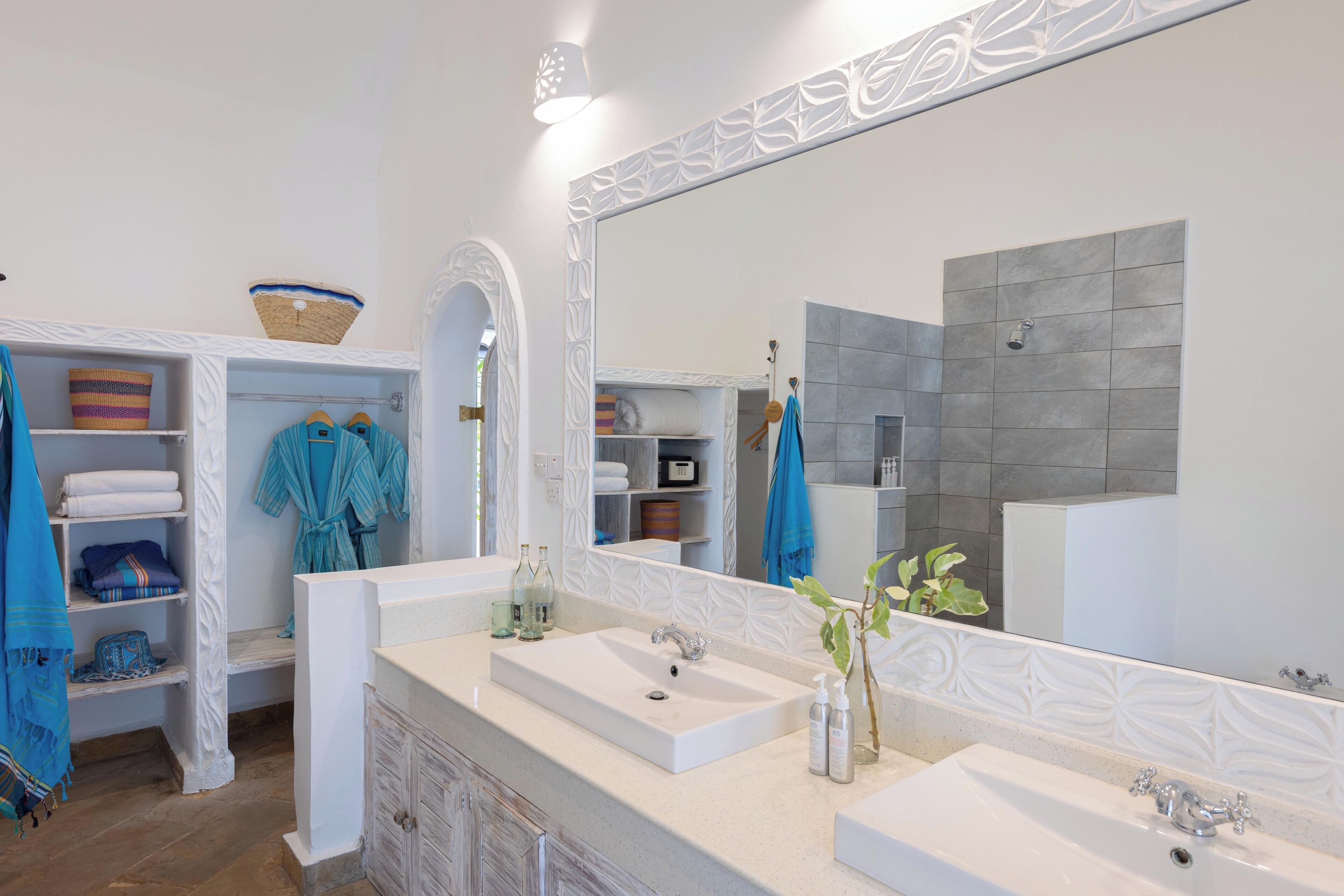 A modern bathroom with two sinks, a large mirror, and a shower area.