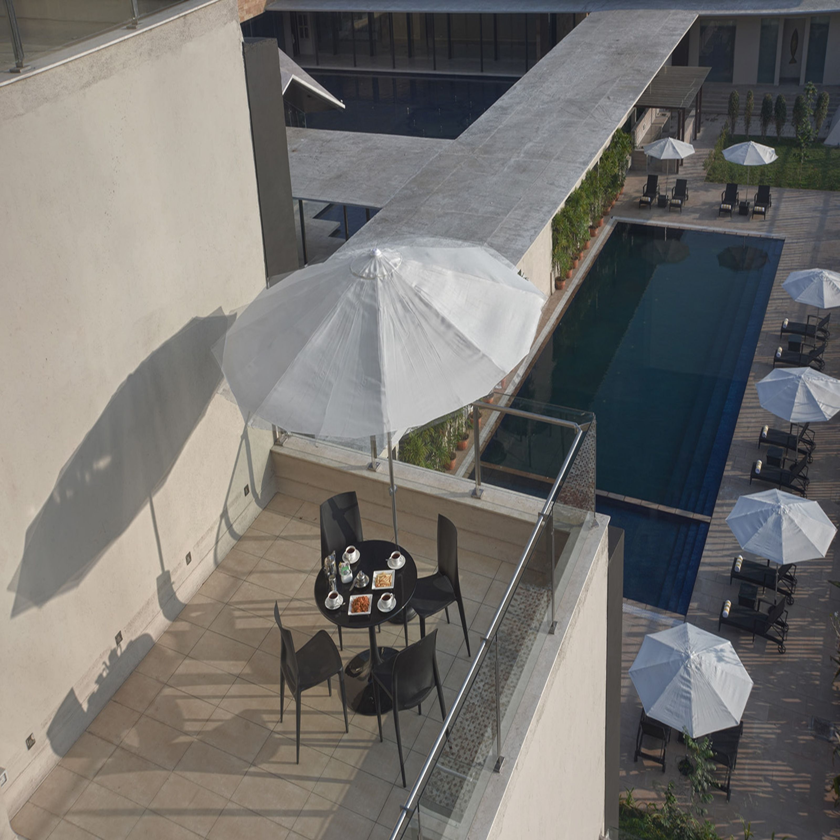 A rooftop terrace with a pool, outdoor seating, and umbrellas.