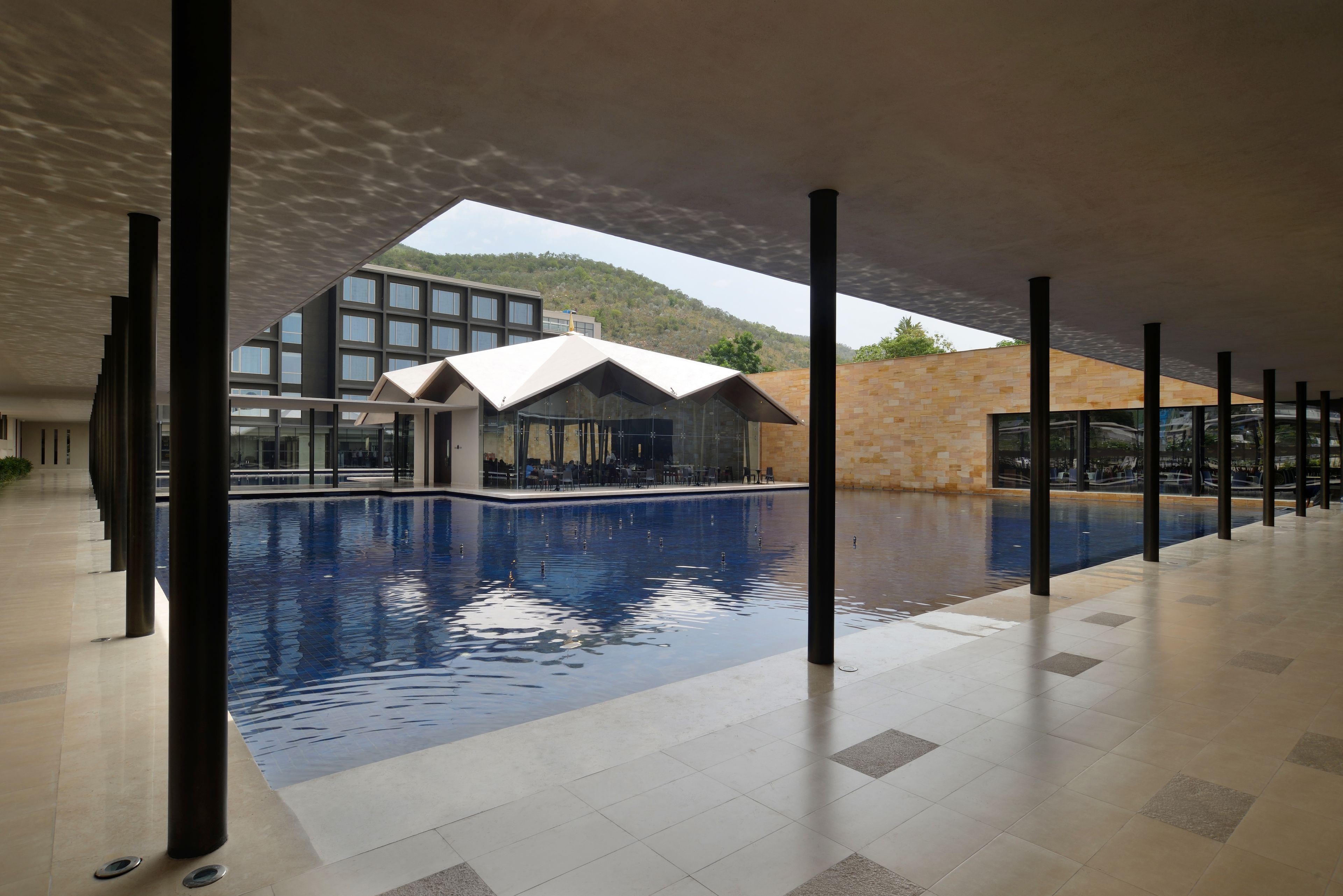 Une piscine dotée d’une architecture moderne, entourée d’une galerie couverte soutenue par des piliers.