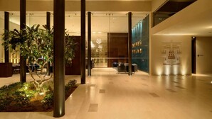 A spacious lobby with a central plant area, a reception desk, and a modern chandelier. - Marasa Sarovar Premiere Tirupati (Tirupati)