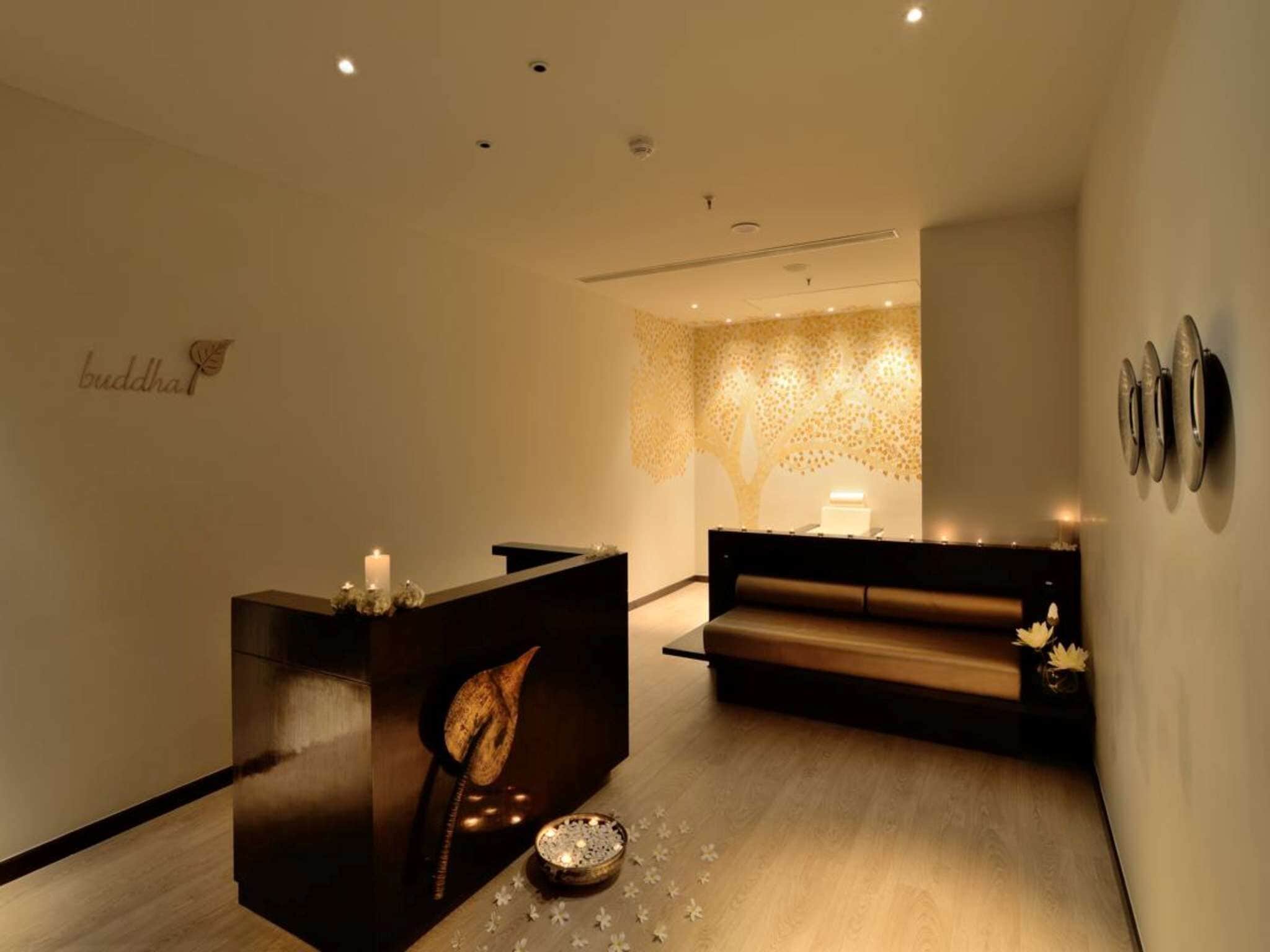 A reception area with a wooden reception desk, a bench, and a wall with a 'buddha' sign.