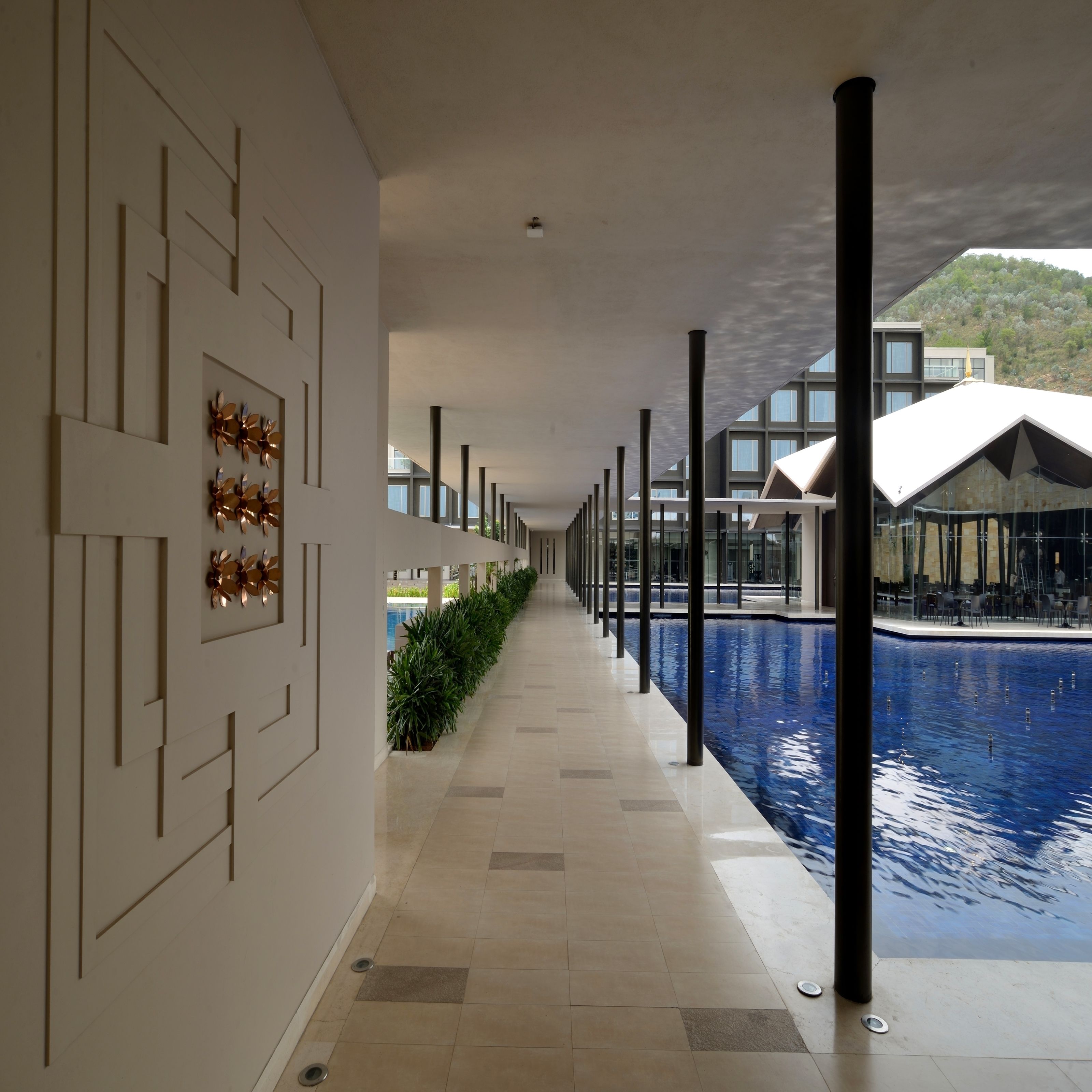 A corridor with a pool, featuring a modern architectural design with geometric patterns on the walls and a clear view of the pool area.