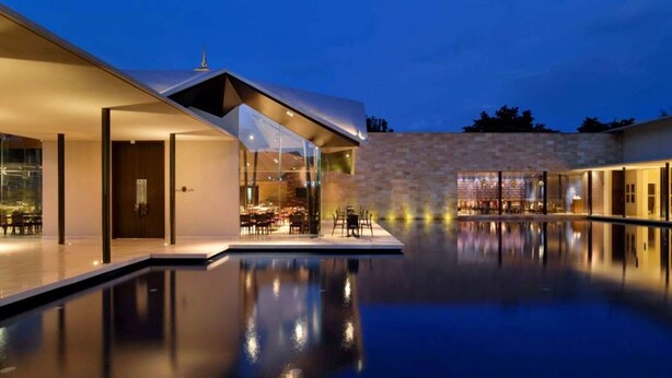 A modern building with a swimming pool, glass walls, and outdoor seating. - Marasa Sarovar Premiere Tirupati (Tirupati)