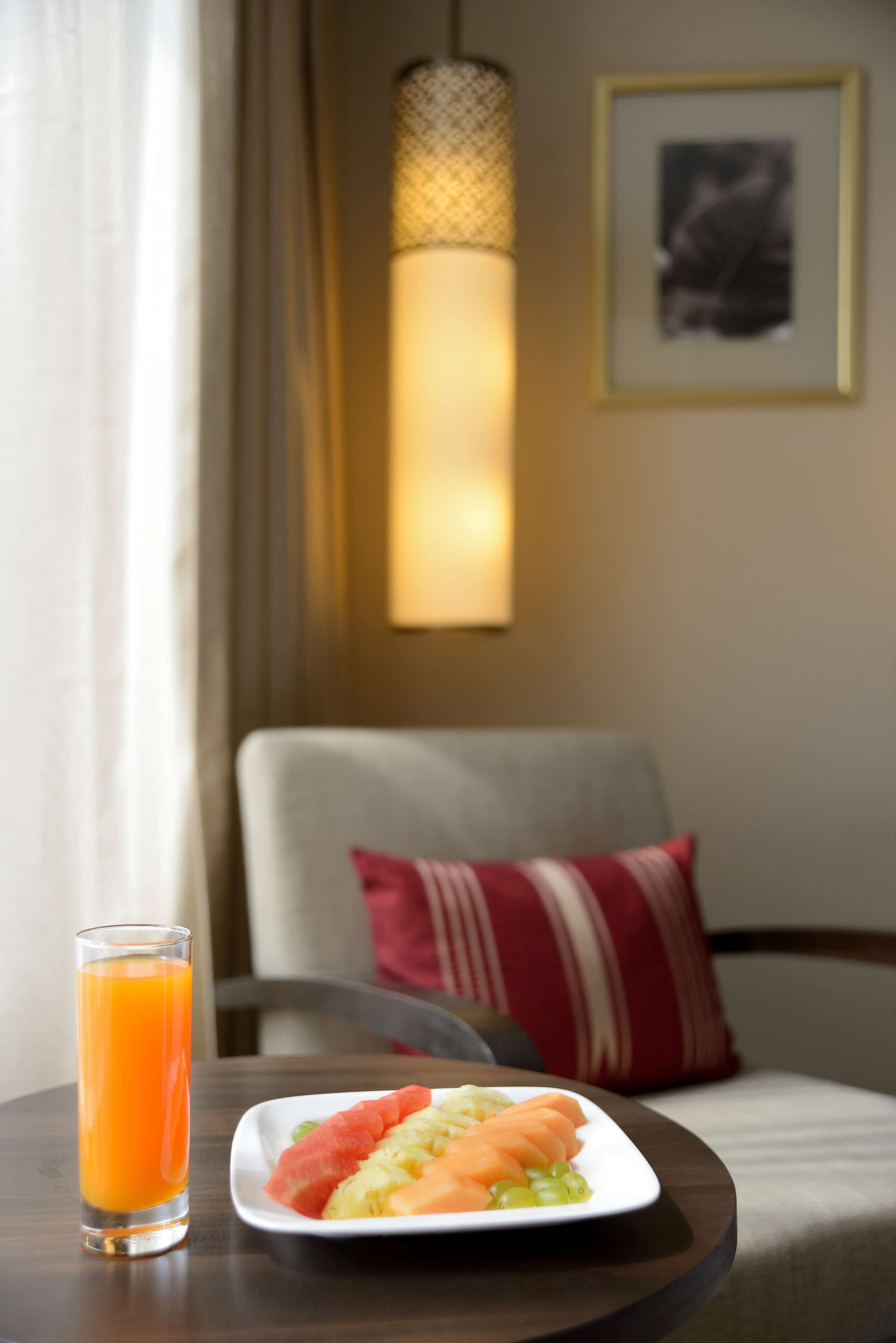 A dining table with a plate of food and a glass of orange juice.