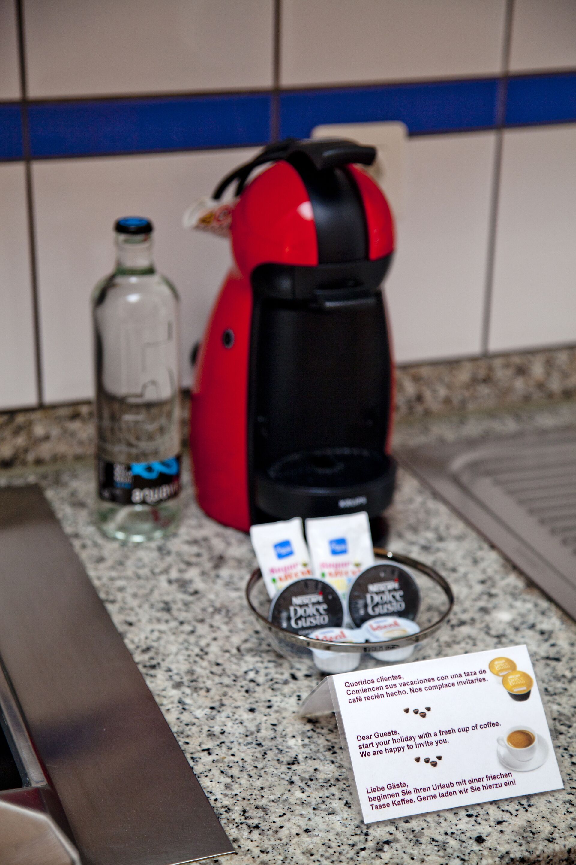 A coffee maker, a bottle of water, and a coffee pod on a kitchen counter.