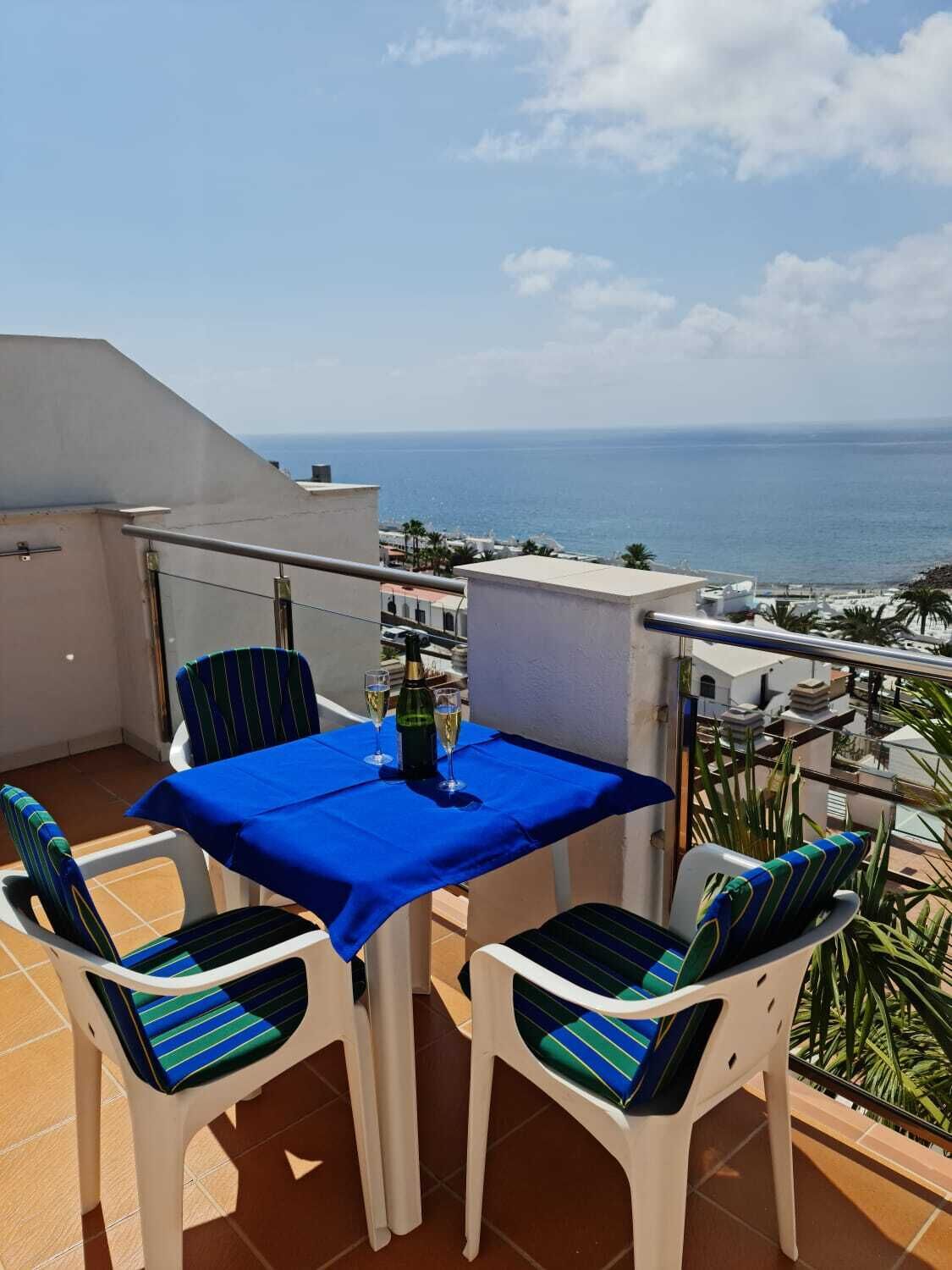 Un balcón con una mesa lista para dos personas, con vista al mar.