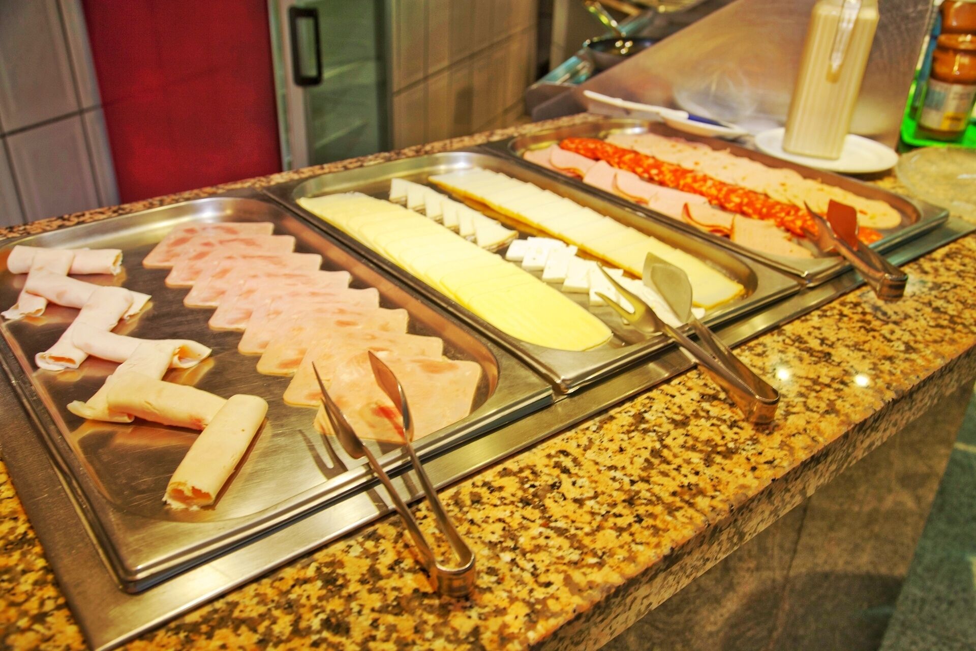 A buffet with various food items including sliced meats and cheeses.