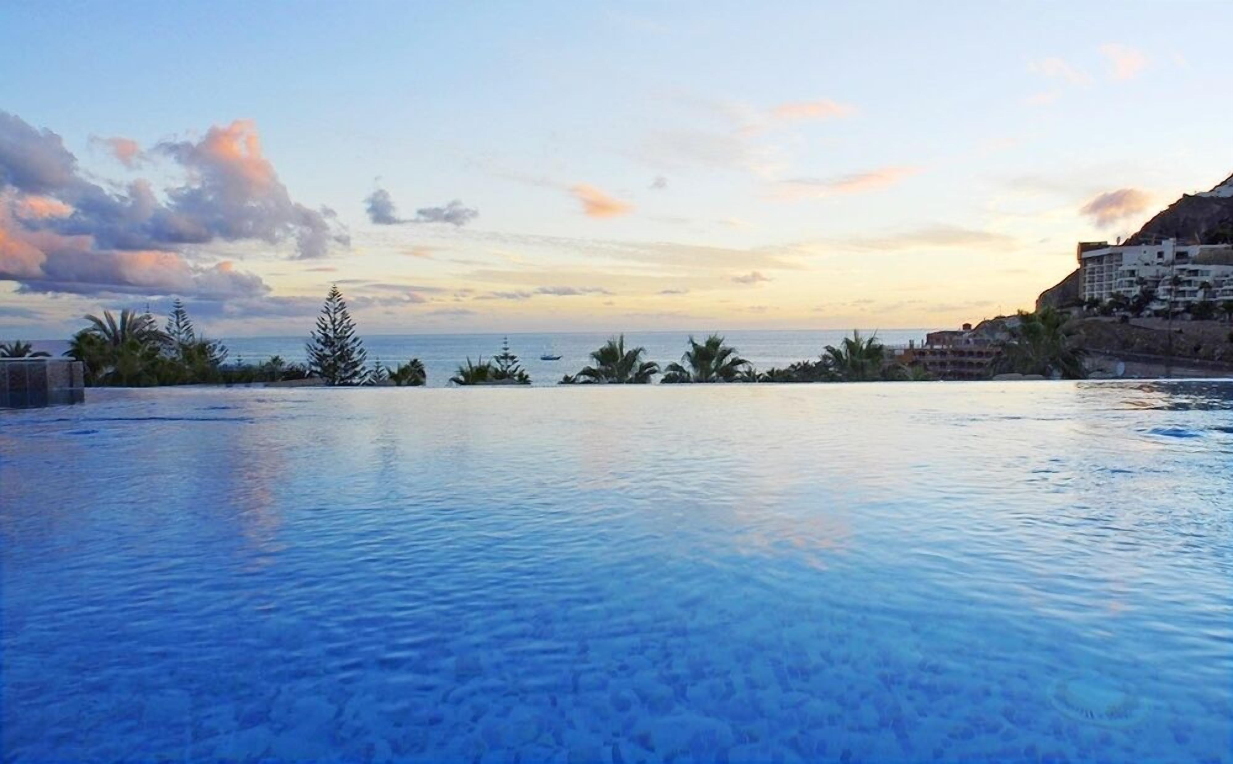 Une vue dégagée sur une piscine, avec un coucher de soleil en arrière-plan.