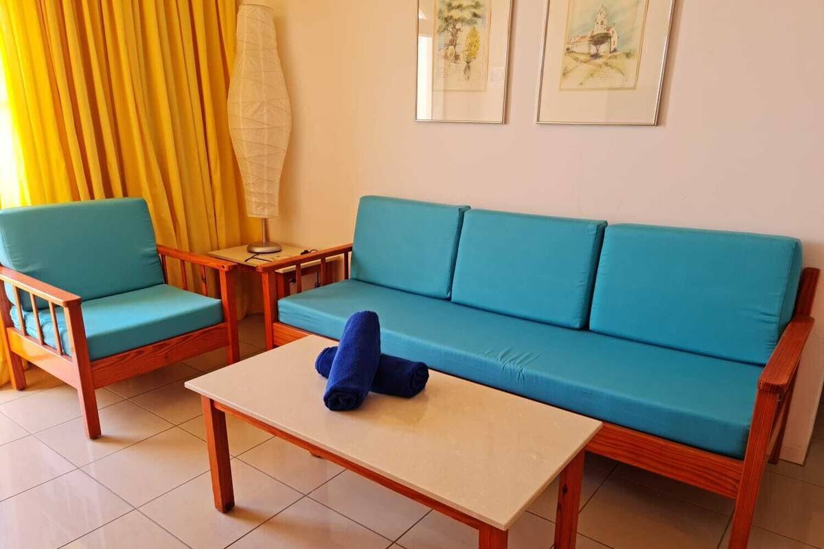 A room with a blue sofa, a matching armchair, and a small wooden table.