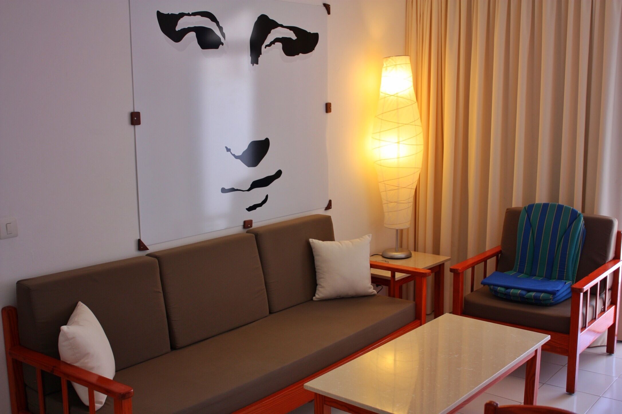 Un salon comprenant un canapé, une table basse, un fauteuil, une lampe et une œuvre d’art murale.